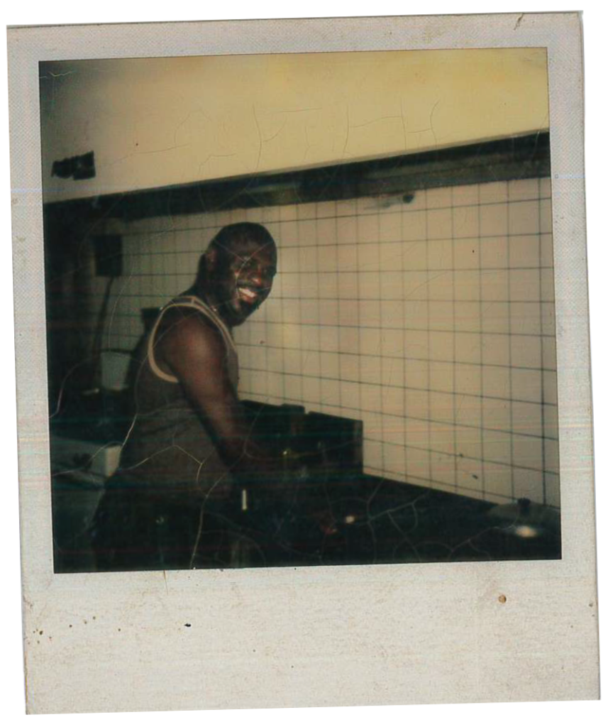 A Polaroid photo of a man standing, smiling in a kitchen